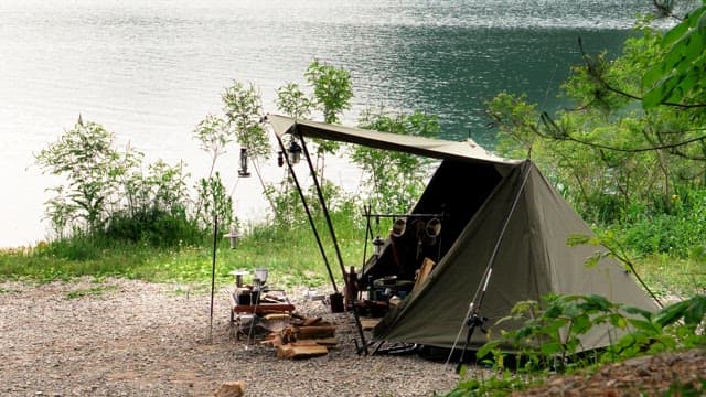 Tent on a quiet lakeside surrounded by lush greenery