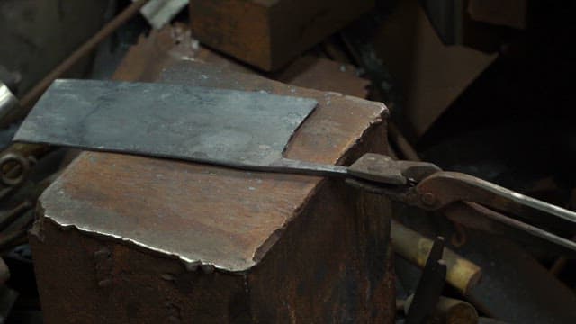 Hammering a metal blade on an anvil