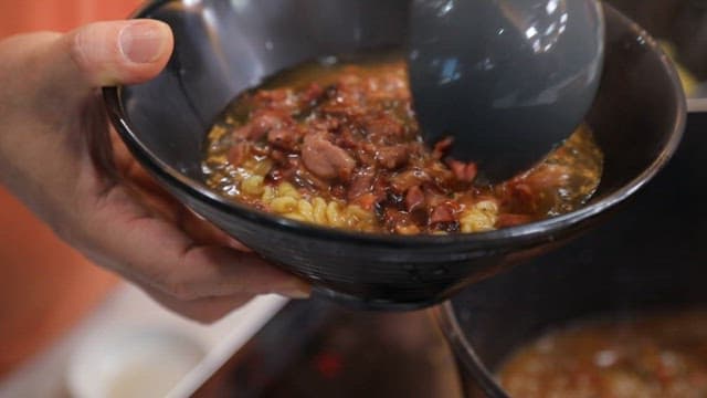 베이컨이 들어간 먹음직스러운 라면을 검은 그릇에 담는 모습