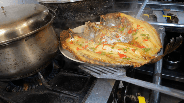 Steamed rockfish being plated in kitchen