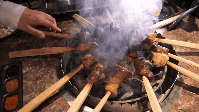 Primitive skewers grilling over charcoal brazier