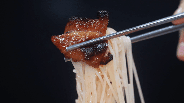 Chopsticks holding noodles and meat