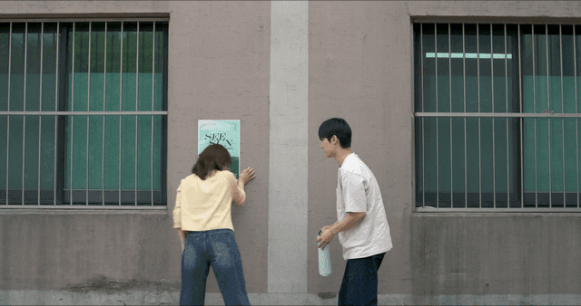 Two people posting poster on wall