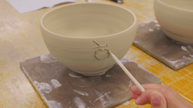 Person engraving letters on ceramic bowl