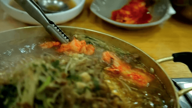 끓고있는 불고기 전골에 김치를 넣는 모습