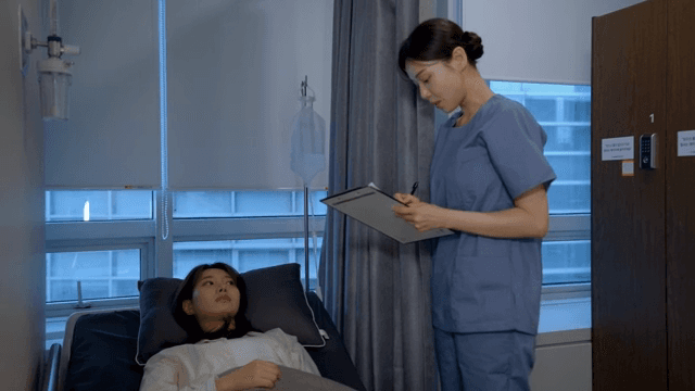 병실 속 환자의 건강상태를 확인하는 간호사