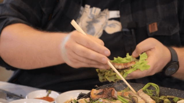 Preparing lettuce wraps with Grilled Pork Belly and water parsley