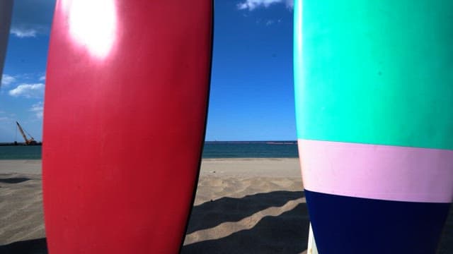 Surfboards arranged on a sandy beach under a clear blue sky