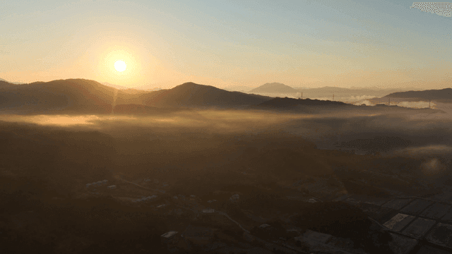 산과 안개 낀 들판 위의 일출