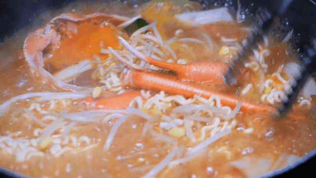 Red crab ramen boiling in pot