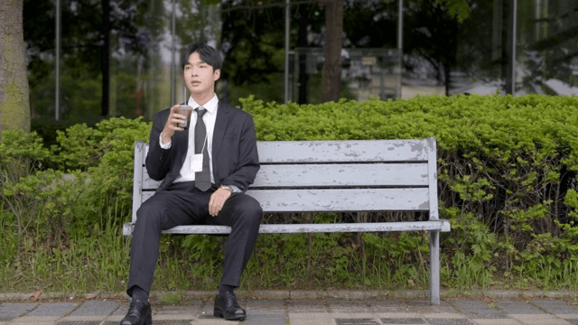 Man sitting on a bench, drinking coffee and catching his breath