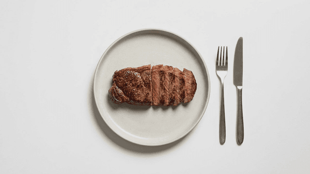 Sliced steak on a plate with cutlery
