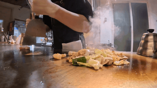Chef skillfully removing shrimp tail on hot griddle