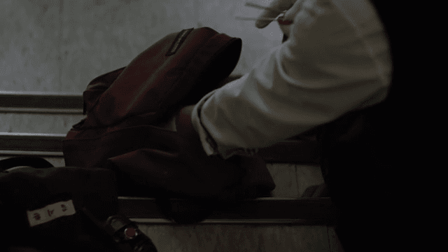 계단에 앉아 가방에서 위험물을 꺼내는 사람