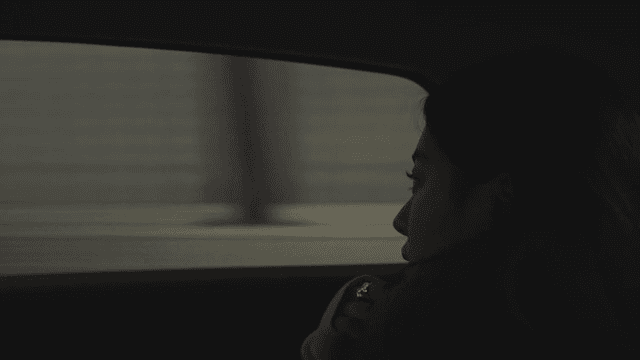 Profile of a woman looking out the window of a taxi at a busy road