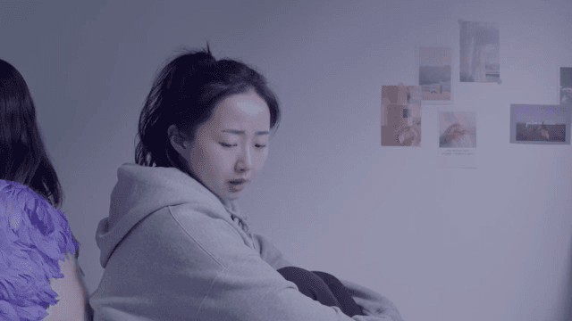 실내에서 등을 맞대고 앉아 있는 두 여성