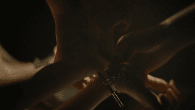 Hands in handcuffs in a dimly lit room