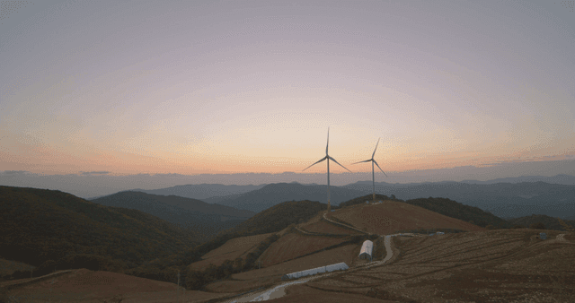 일출에 언덕 위의 풍력 터빈