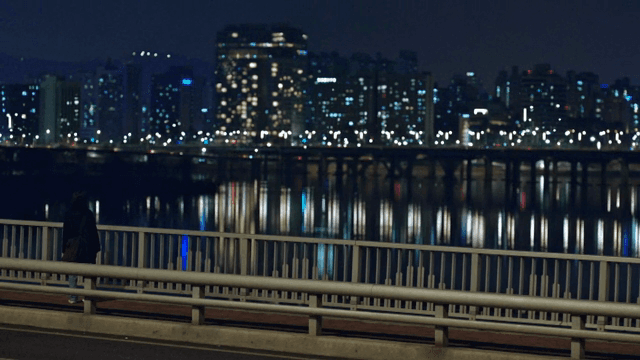 도시의 불빛이 비치는 밤에 다리 위에 있는 사람