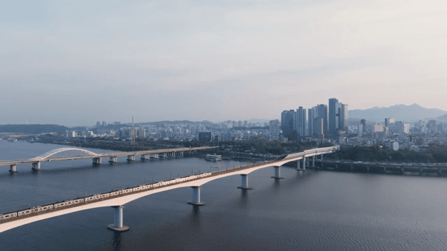 Train passing over city skyline and bridge over river