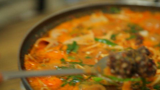 Broth of boiling stew made with sundae, mushrooms, and vegetables