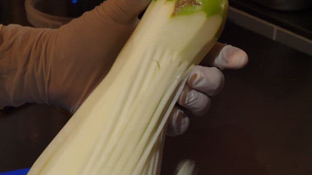 Person Peeling a Large Radish in a kitchen