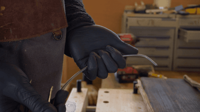 사람이 펜치를 사용하여 금속 와이어를 구부리는 모습