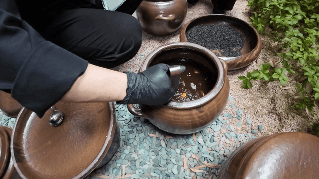 A spoon scooping soy sauce from a pot