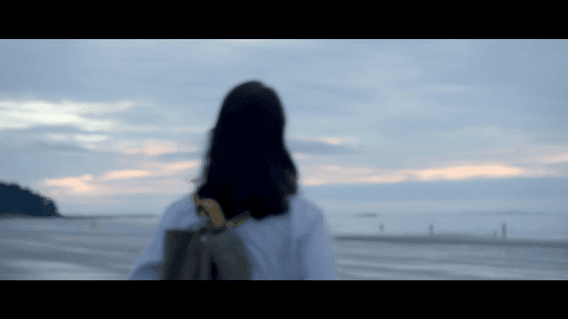 Quiet beach at dawn and back of woman carrying backpack