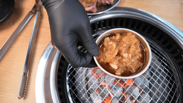 Hand placing garlic marinade on grill