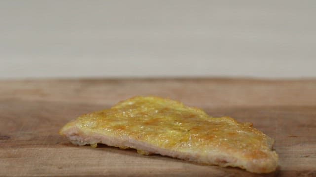 Golden brown meat pancake topped with spicy seasoned green onion on a wooden board