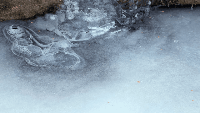 Frozen stream surrounded by snow and rocks