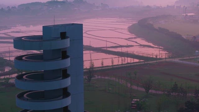 Serene landscape with rice fields and a spiral building