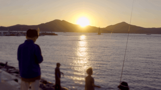 People fishing by the sea at sunset