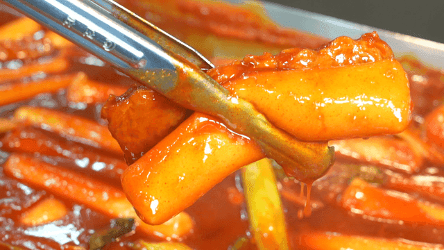 Spicy tteokbokki picked up with tongs