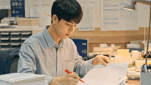 Man grading test papers at desk