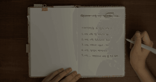 책상 위에서 일기를 쓰는 사람