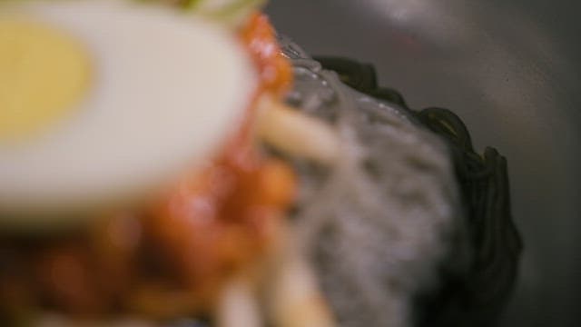 달걀이 얹어진 빨간 양념의 비빔 냉면