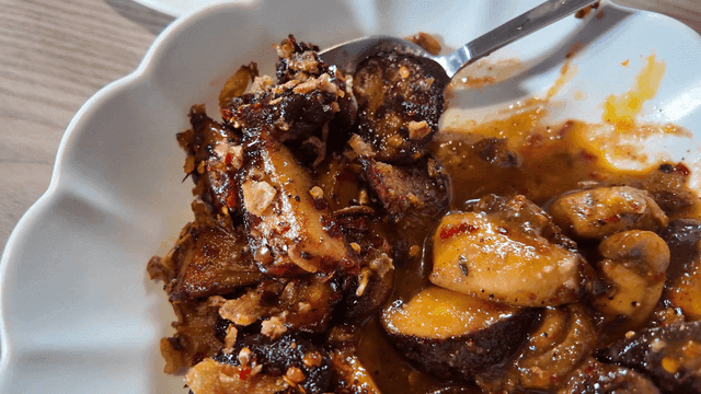 Spoon scooping up spicy mushroom dish from plate