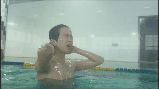Man emerging from water of indoor swimming pool