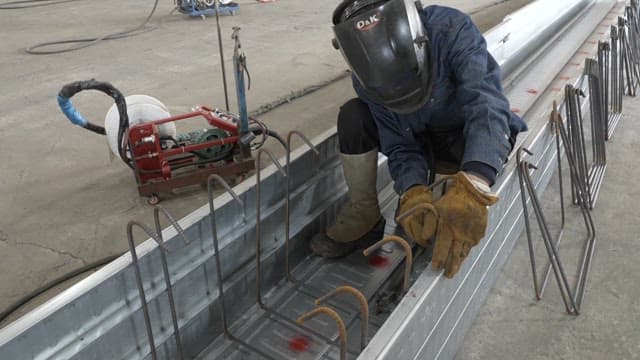 Worker welding metal beams in a factory