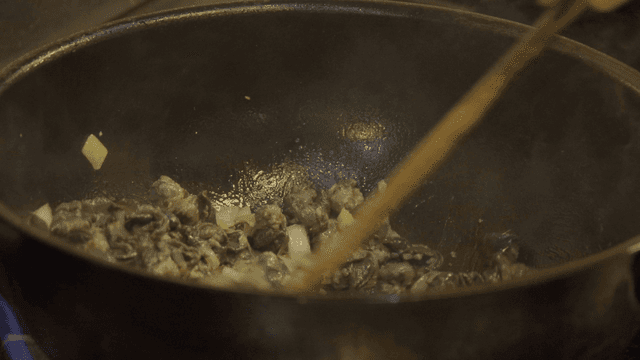Stir-fried chicken gizzards in wok on stove