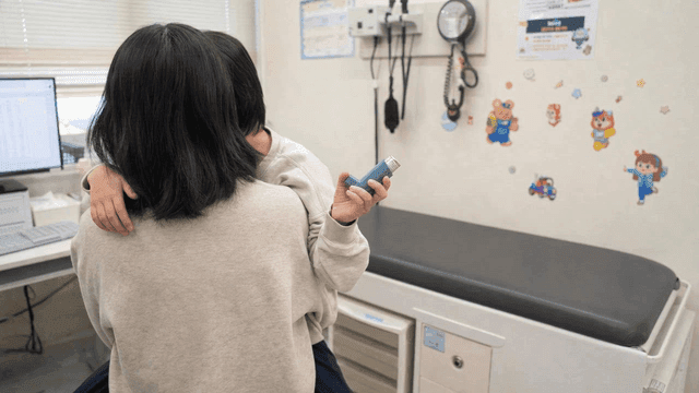 Child holding inhaler in examination room