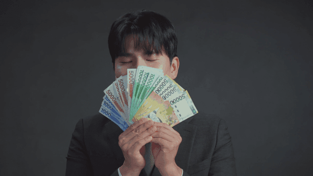 만족스러운 표정으로 돈 냄새를 맡는 남자