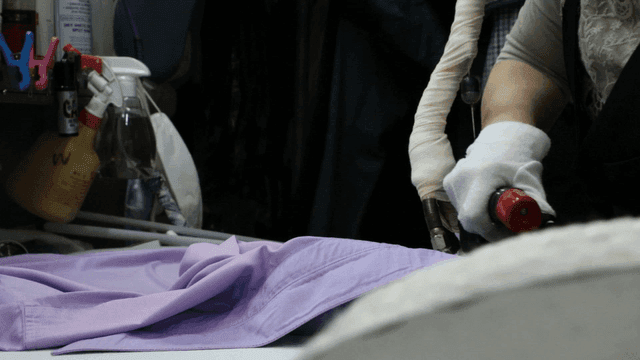 Ironing a purple shirt in a laundry room