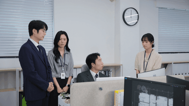 책상 주위에 모여 꾸중을 듣는 사무실 직원들