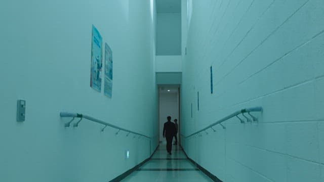 Person walking down a long, narrow hallway inside a building