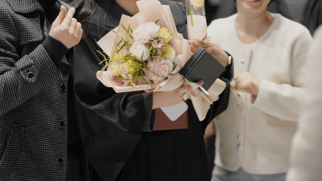 Graduates taking commemorative photos with their families, holding bouquets of flowers.