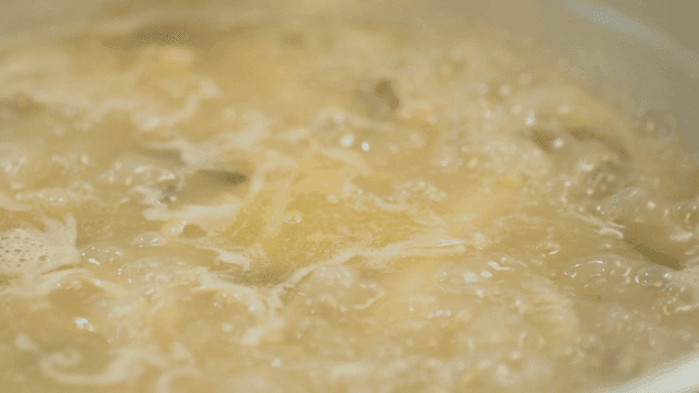Whole chicken broth boiling in pot