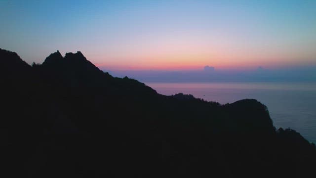 바다 위의 석양과 그림자로 드리운 산